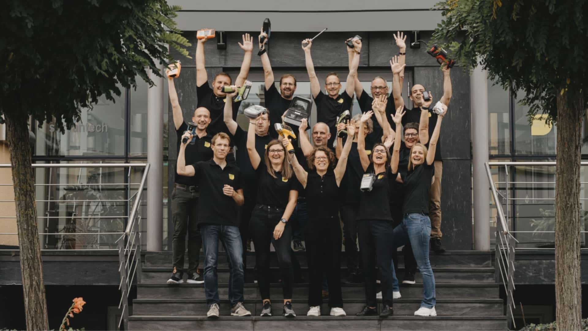 Analyticon team holding devices and having their arms in the air.