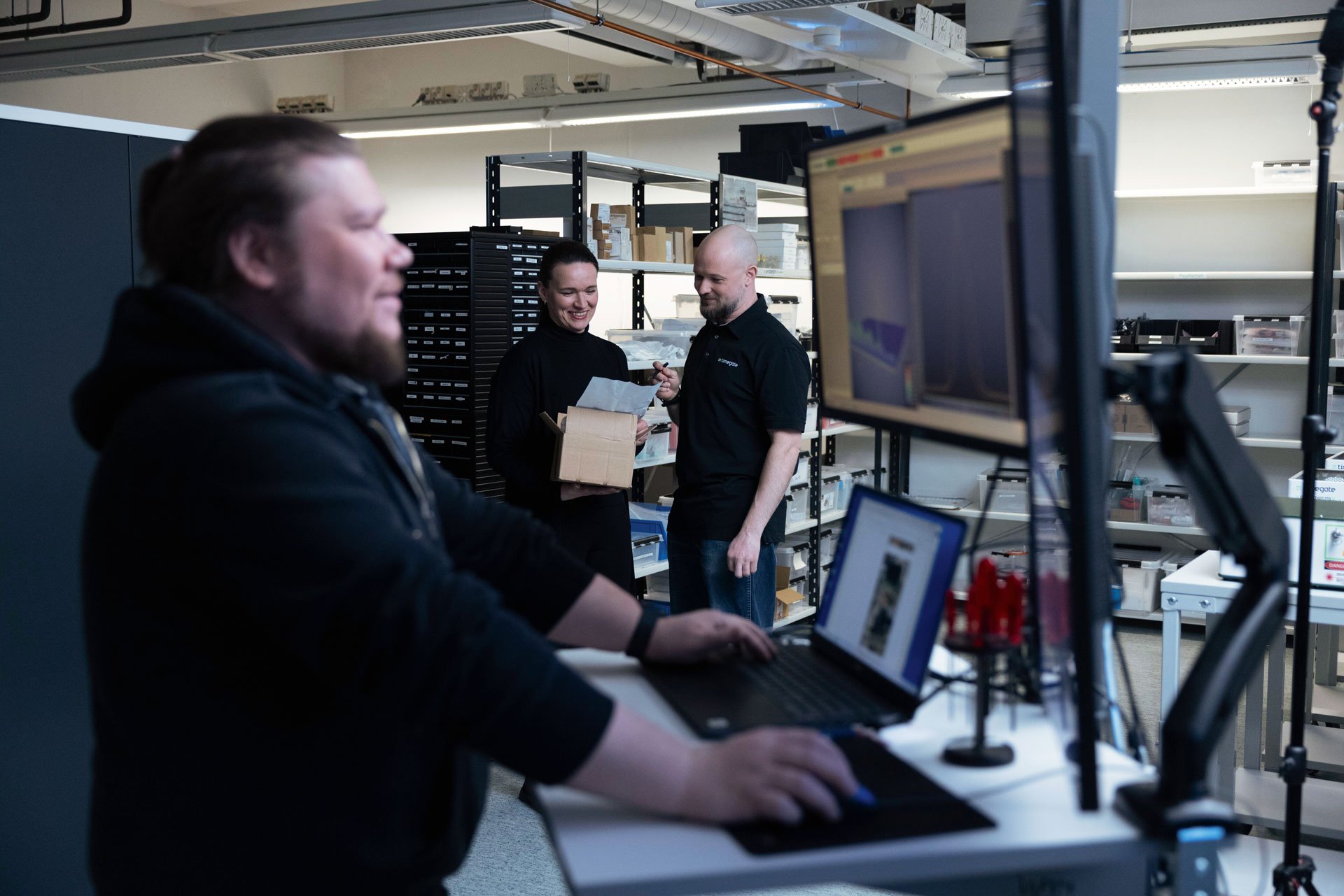 man-watching-screen-and-two-people-discussing-in-background