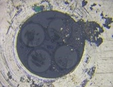Microscope picture of a black, dirty fiber end. 