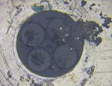 Microscope picture of a black, dirty fiber end.